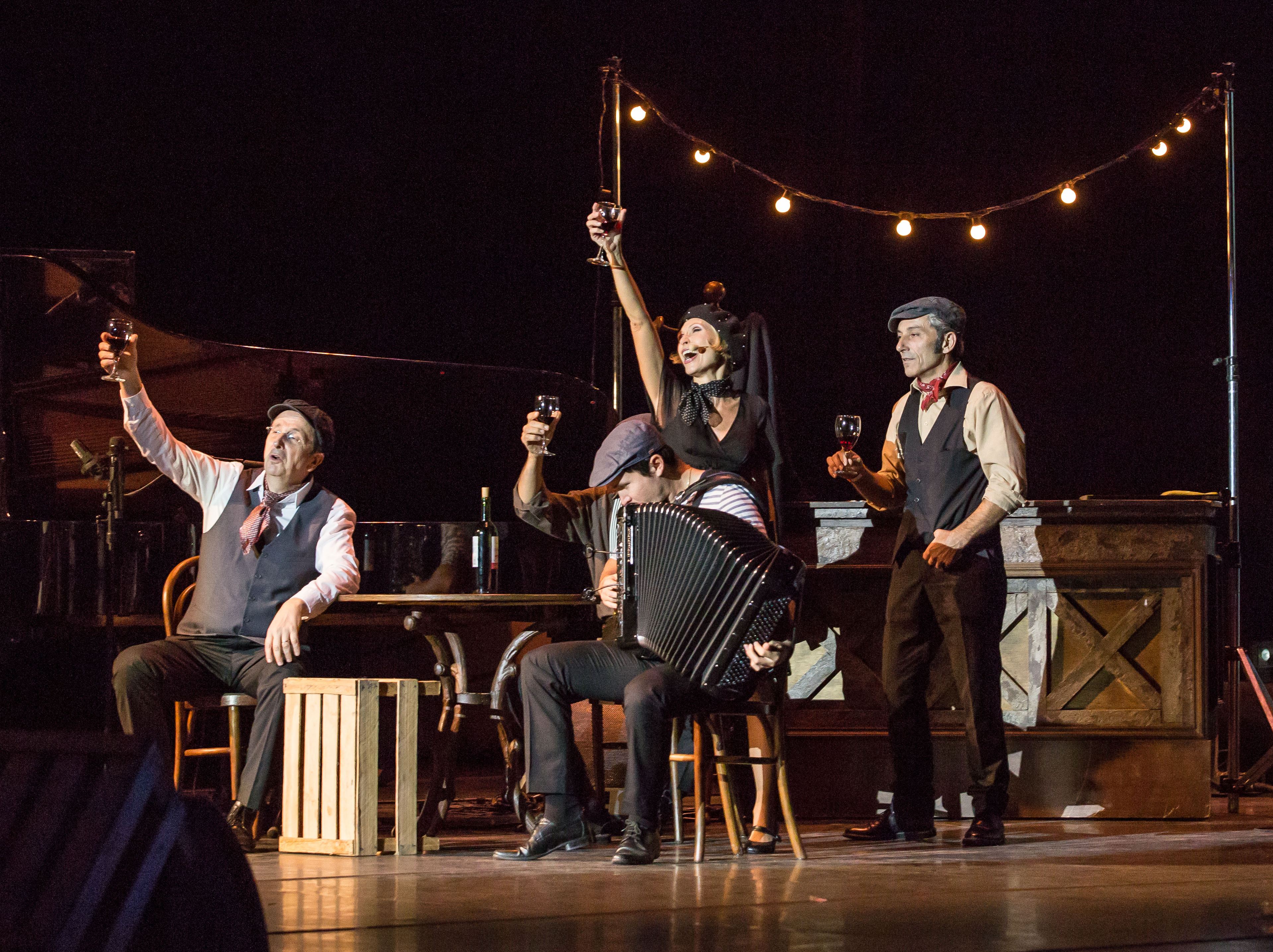 A singer and three musicians on stage, arms extended