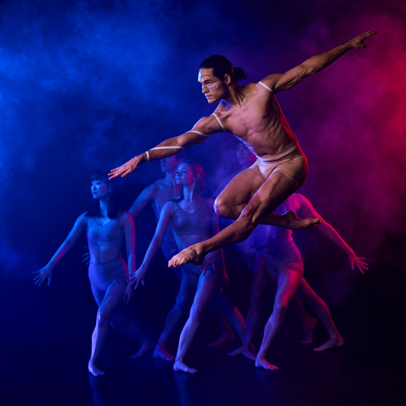 A ballet dancer leaps in the air against a blue and pink background