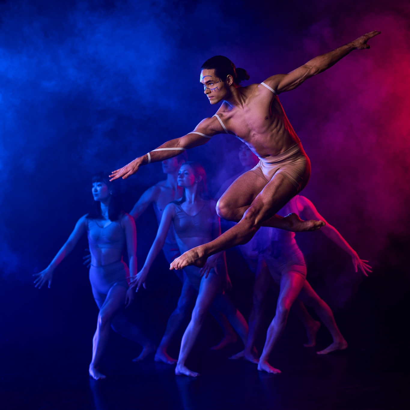 A  ballet dancer leaps in the air against a blue and pink background