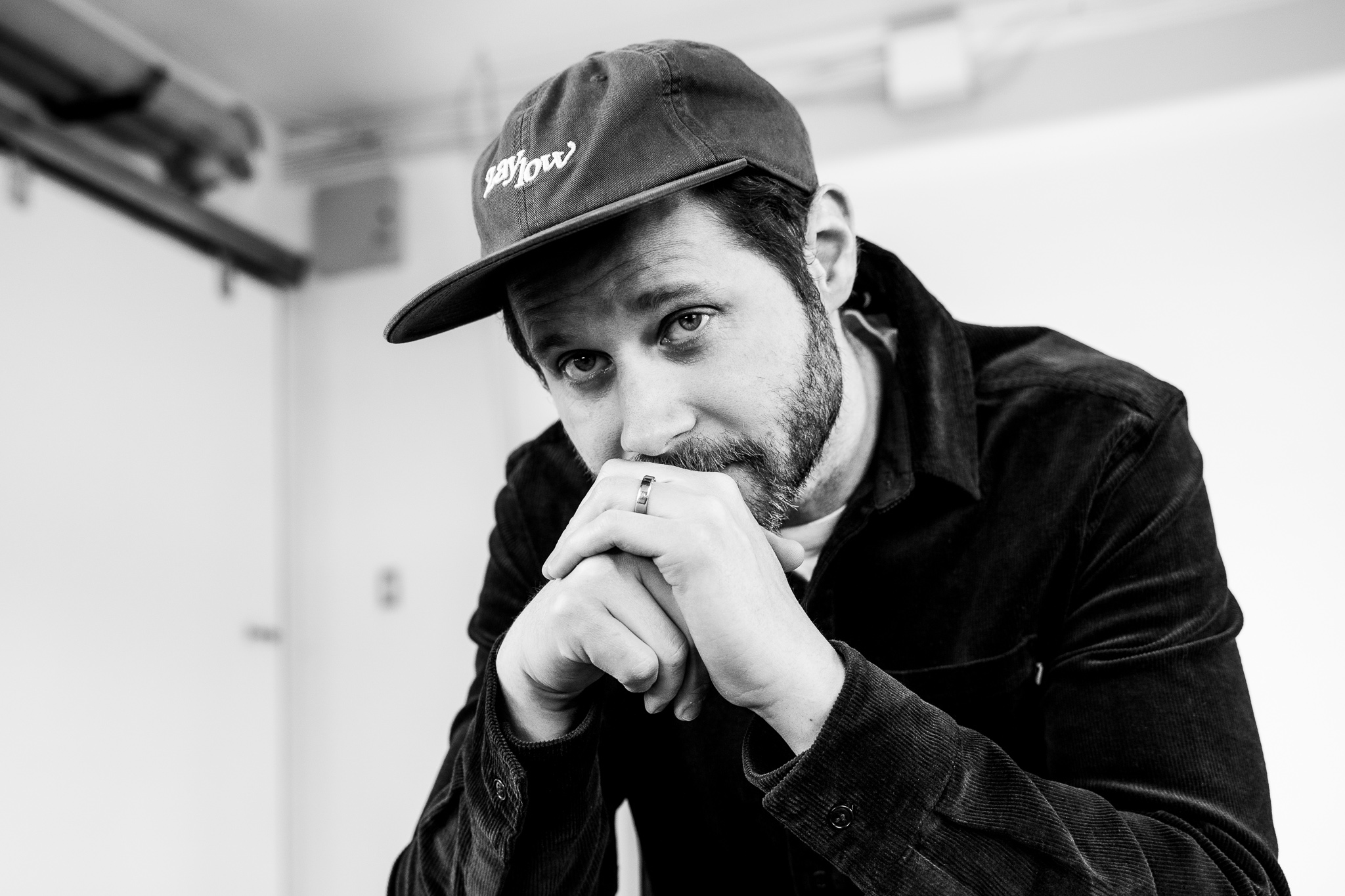 Black and white image of Dan Mangan leaning forward resting his chin on his hands