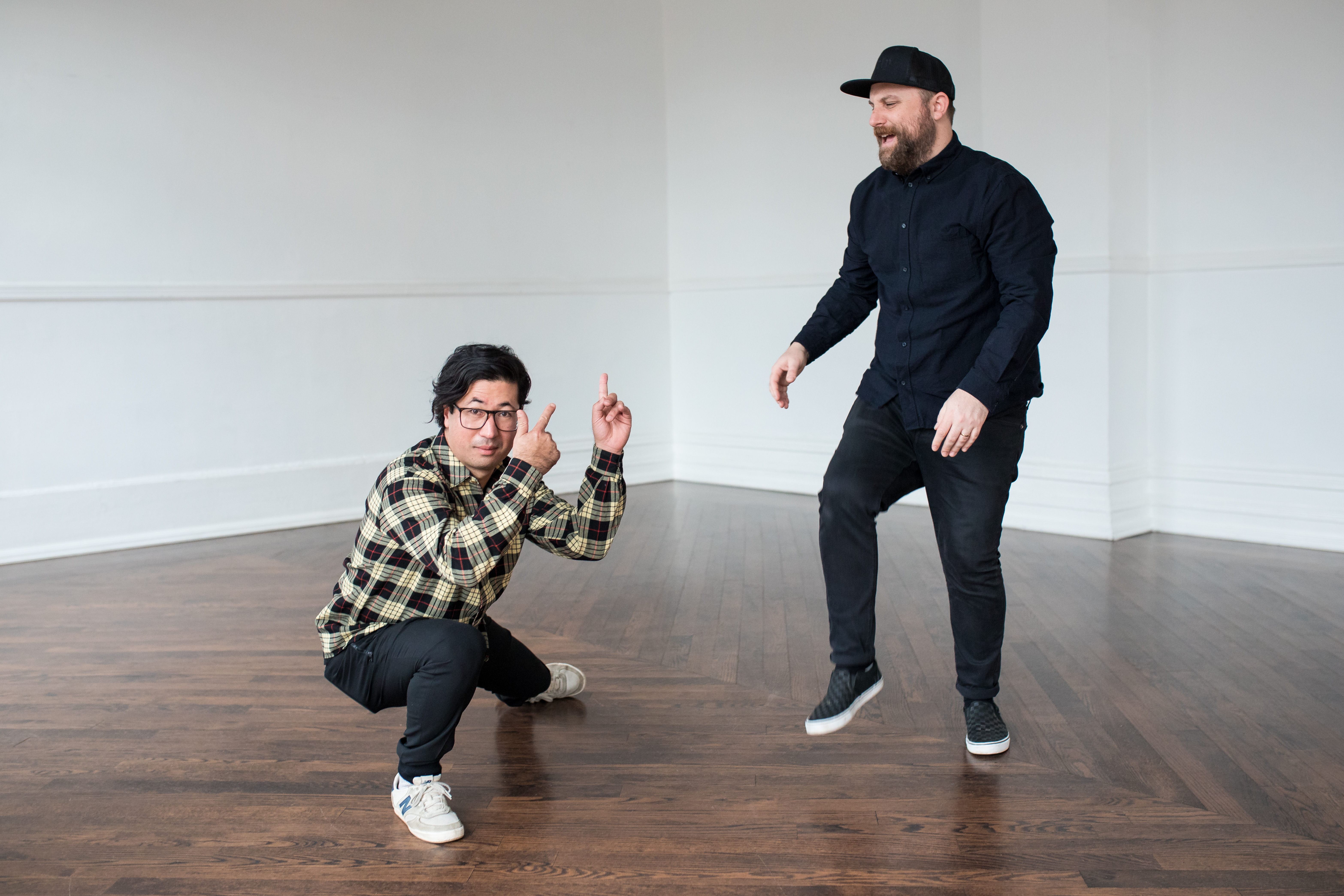 Daveed Goldman and Nobu Adilman are posing in a room with wood flooring