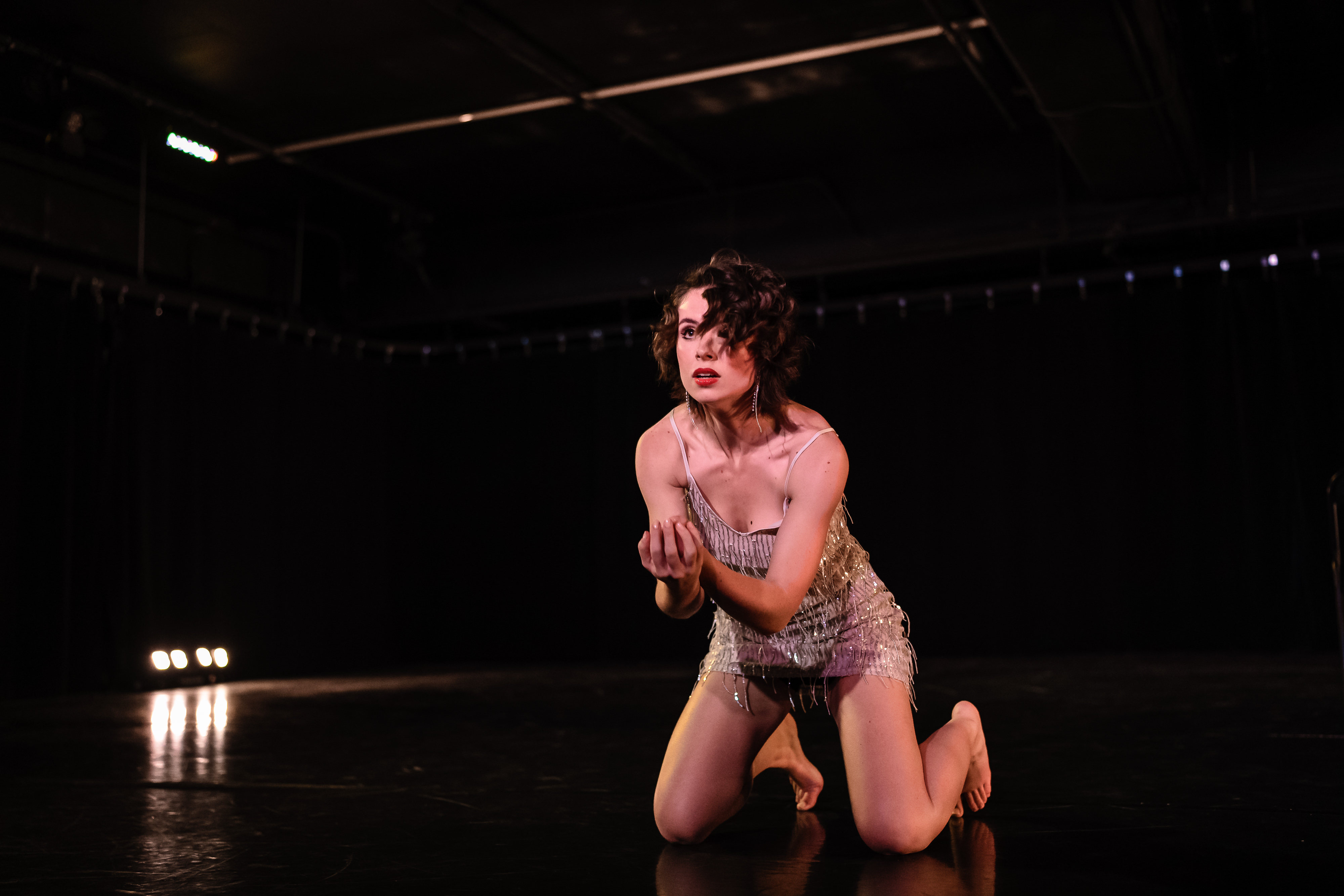Sydney Hallett strikes a pose in the centre of a darkened stage.