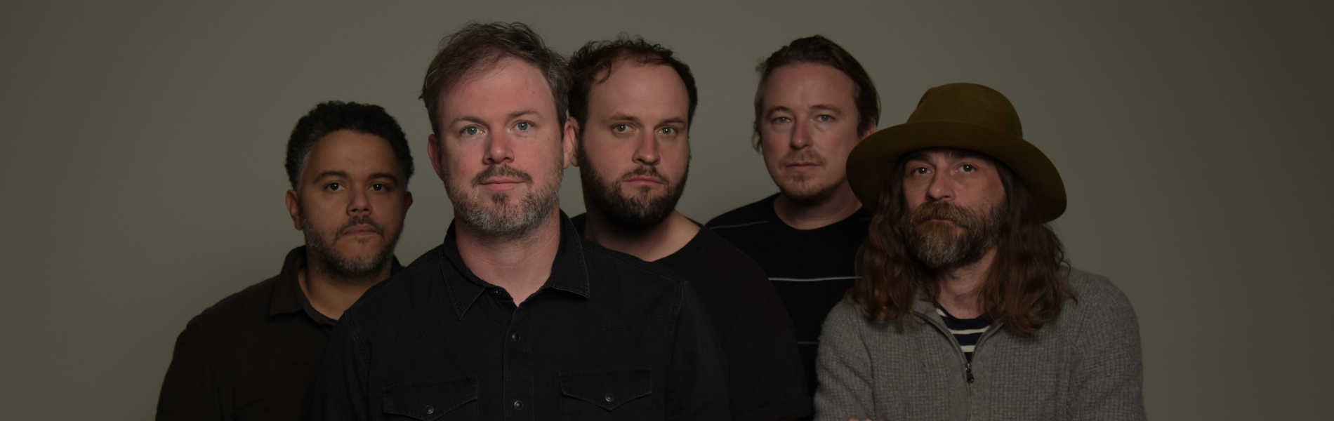 A close up of the five members of Wintersleep standing together looking right at the camera