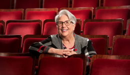 Della Shepherd seated against a background of red theatre seats.