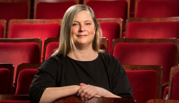 Lesandra Dodson in a black top against a background of red theatre seats.