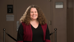 Melissa Cameron in a red and black top, standing in front of a closed theatre door