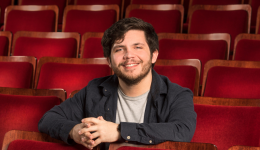 Jason McIntyre in a dark long-sleeved shirt in front of red theatre seats