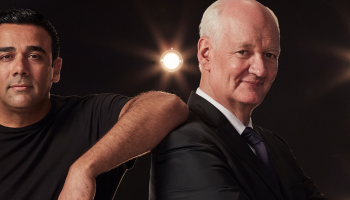 Asad Mecci leaning with an arm on the back of Colin Mochrie