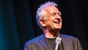 Ron James on stage with a mic in hand.