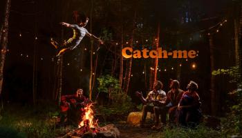 An acrobat flies high over a campfire