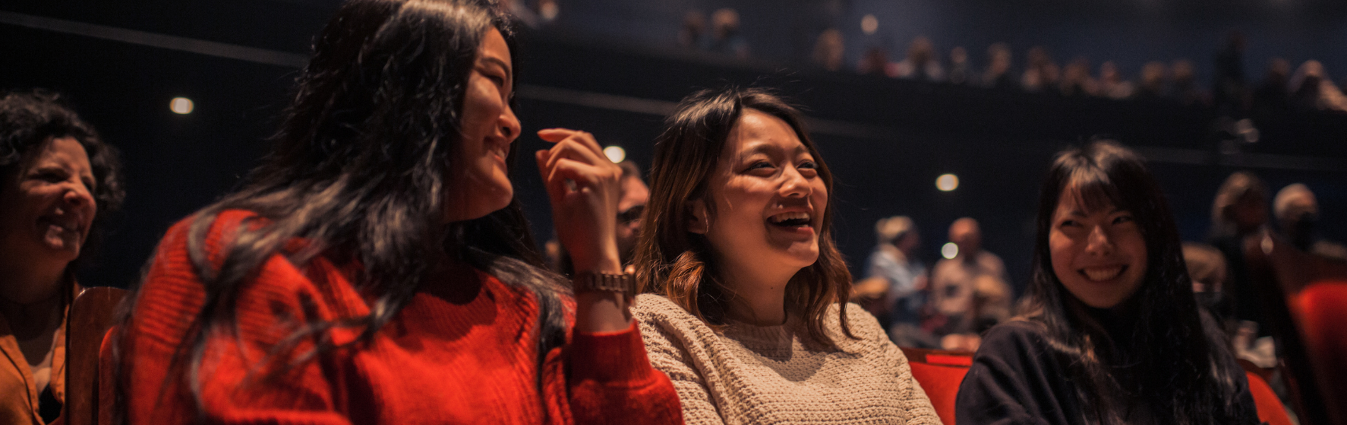 3 women laughing together in audience seats