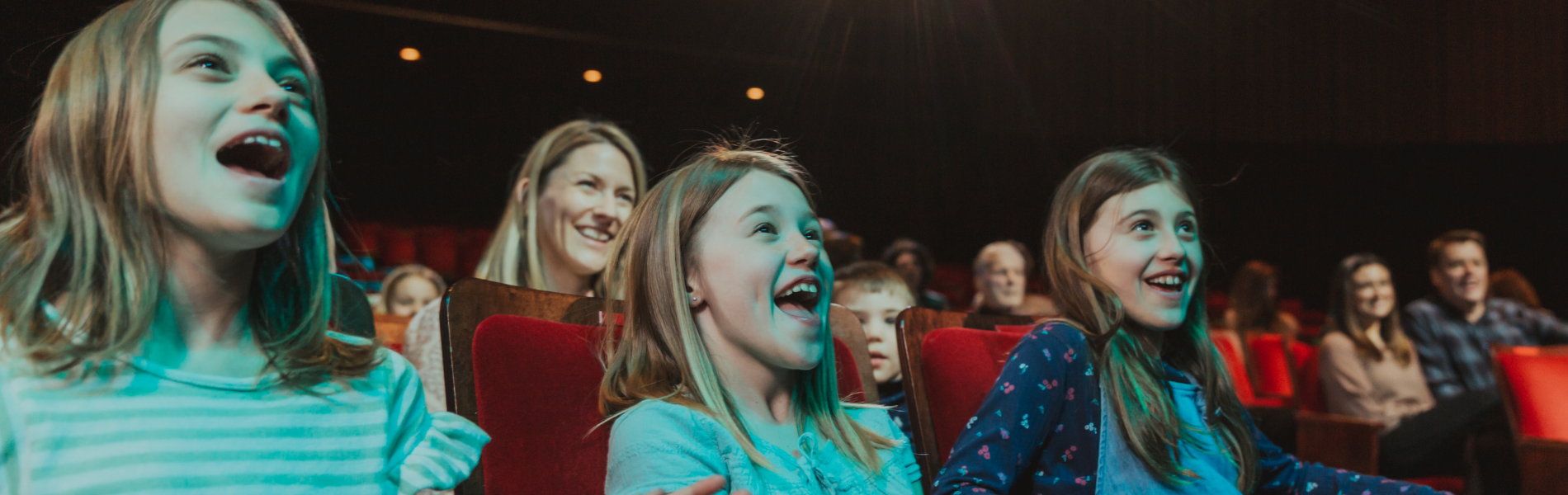 3 children sitting in the front row smiling and laughing