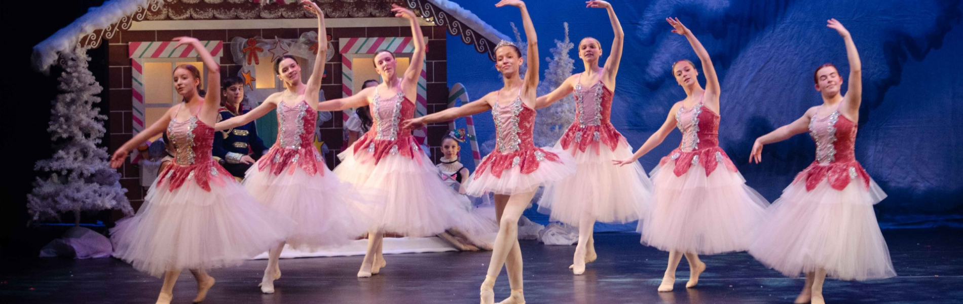 Ballerinas dancing on stage, with the Nutcracker set in the background.