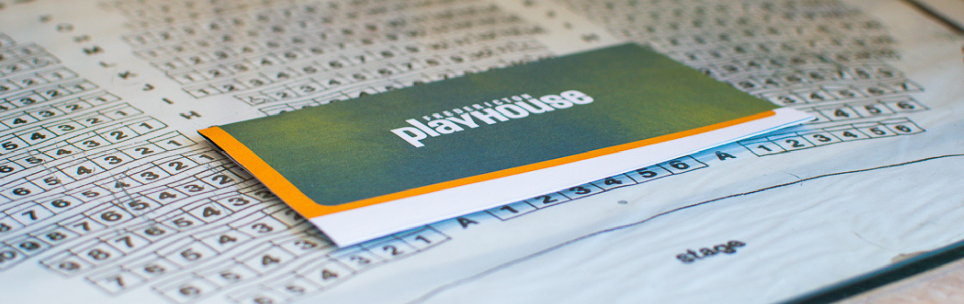 A close up image of a theatre seating map with a ticket holder laying on top of it.