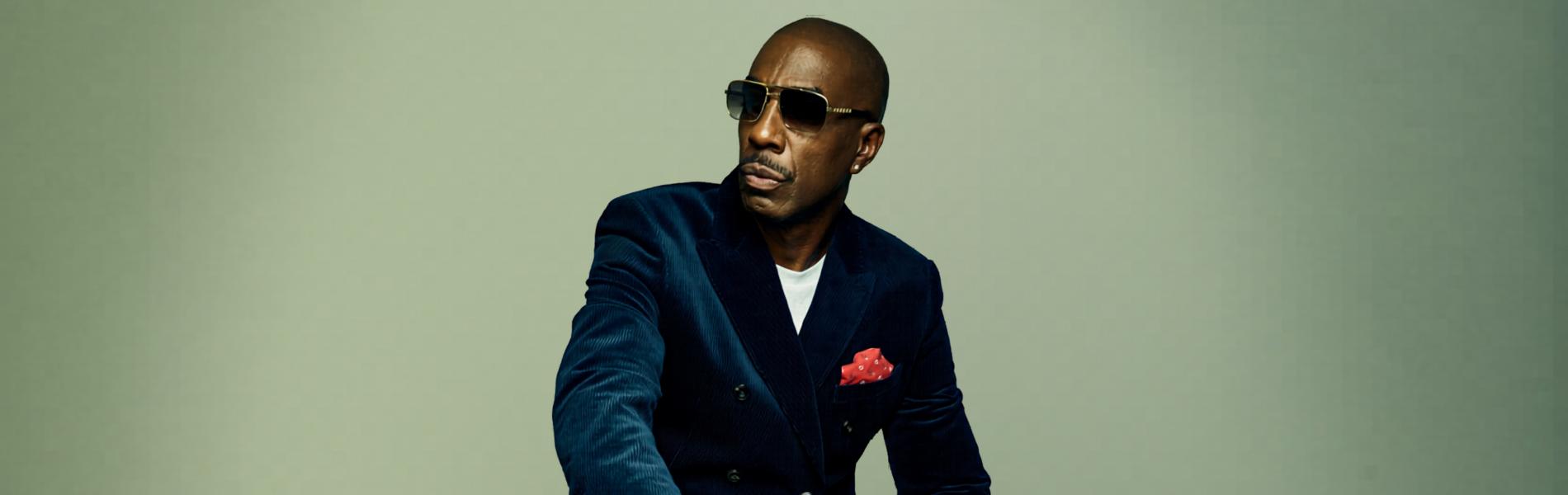 JB Smoove sits, suited.