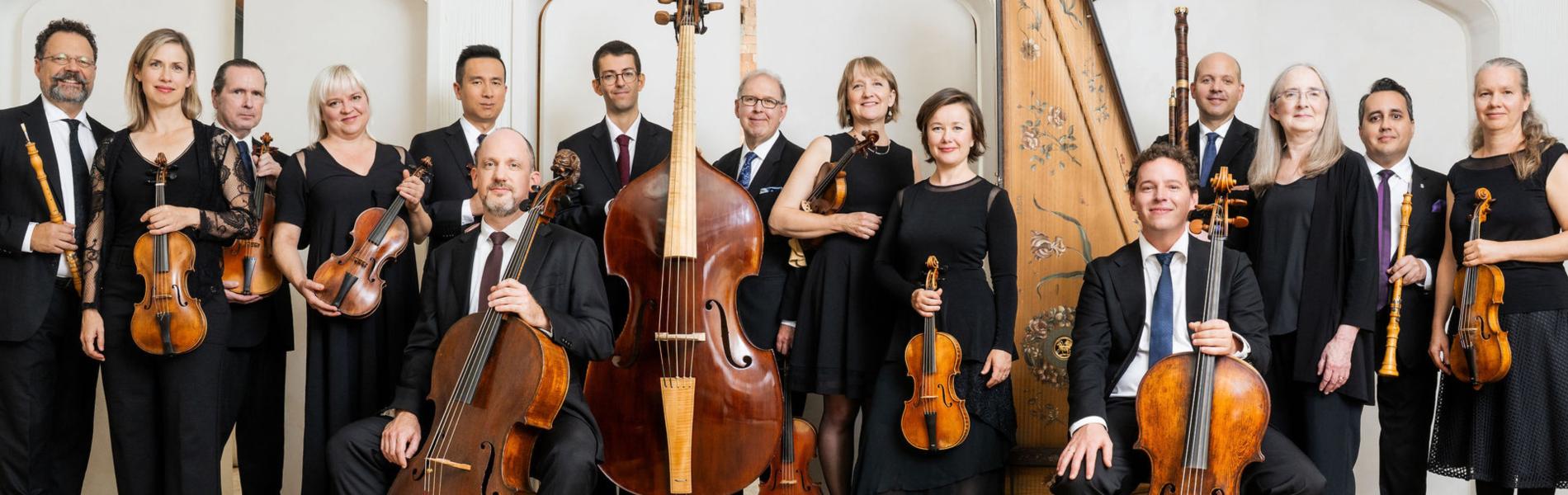 A large amount of suited musicians hold stringed instruments. 