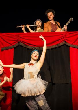 Two performers in front of a curtain with two performers above with musical instruments