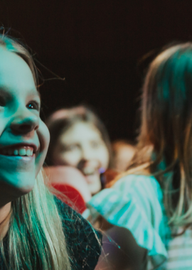 Children in the audience smiling at the stage