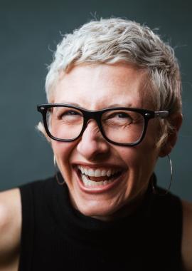 Lisa Anne Ross leans toward the camera, grinning wildlly. 